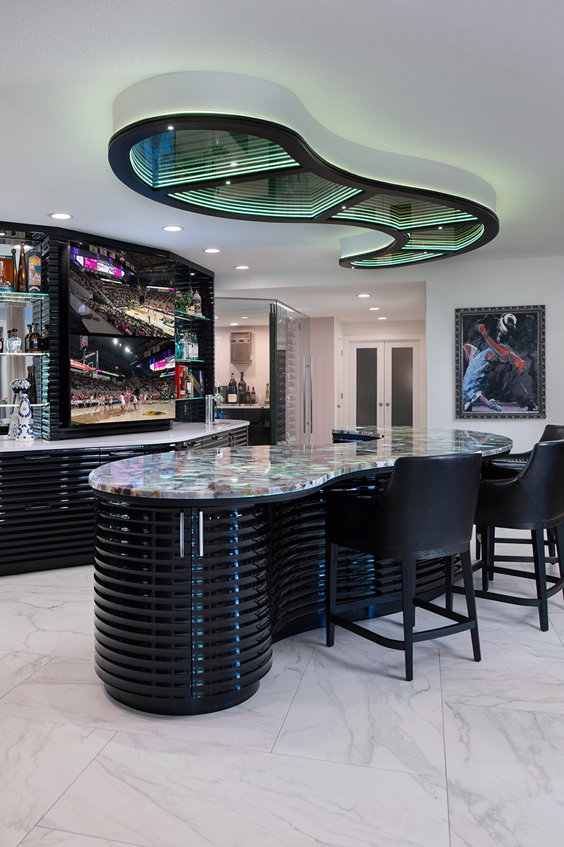 Kleweno custom basement bar and wine cellar Curved waterfall bar island with seating for entertaining guests