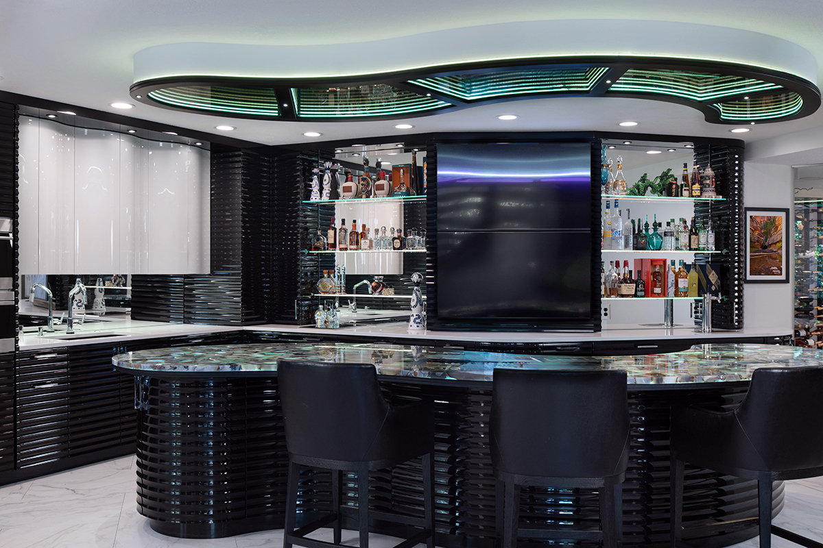 Kleweno custom basement bar and wine cellar Custom home bar featuring a curved island with metallic high-gloss cabinetry